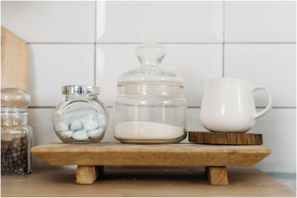 Glass jars filled with granulated sugar, reflecting light against a soft background.